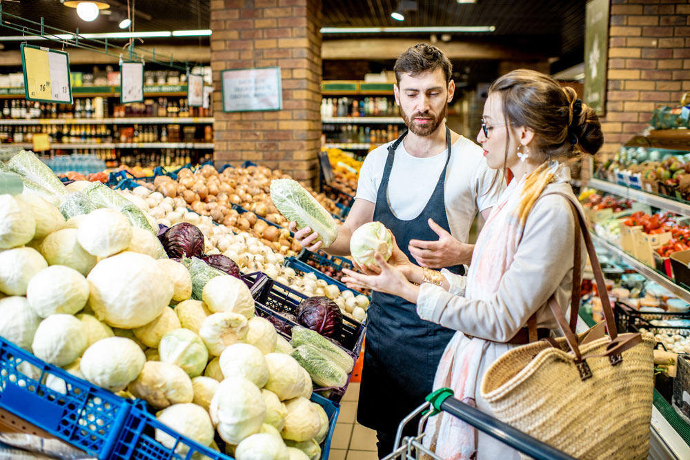 Foto zeigt einen Supermarktmitarbeiter und eine Kundin bei einkaufen